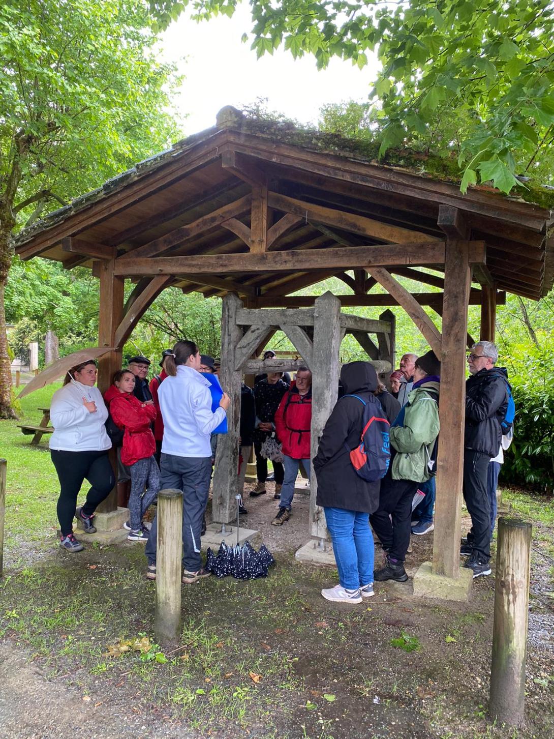 L'animatrice et le groupe de randonneurs sous un travail à ferrer à Poudenas pour s'abriter de la pluie